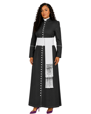 A woman modeling a long black cassock with a wide white waist sash, white vertical paneling, white decorative buttons, and a white fringed hanging detail, shown against a plain white background.