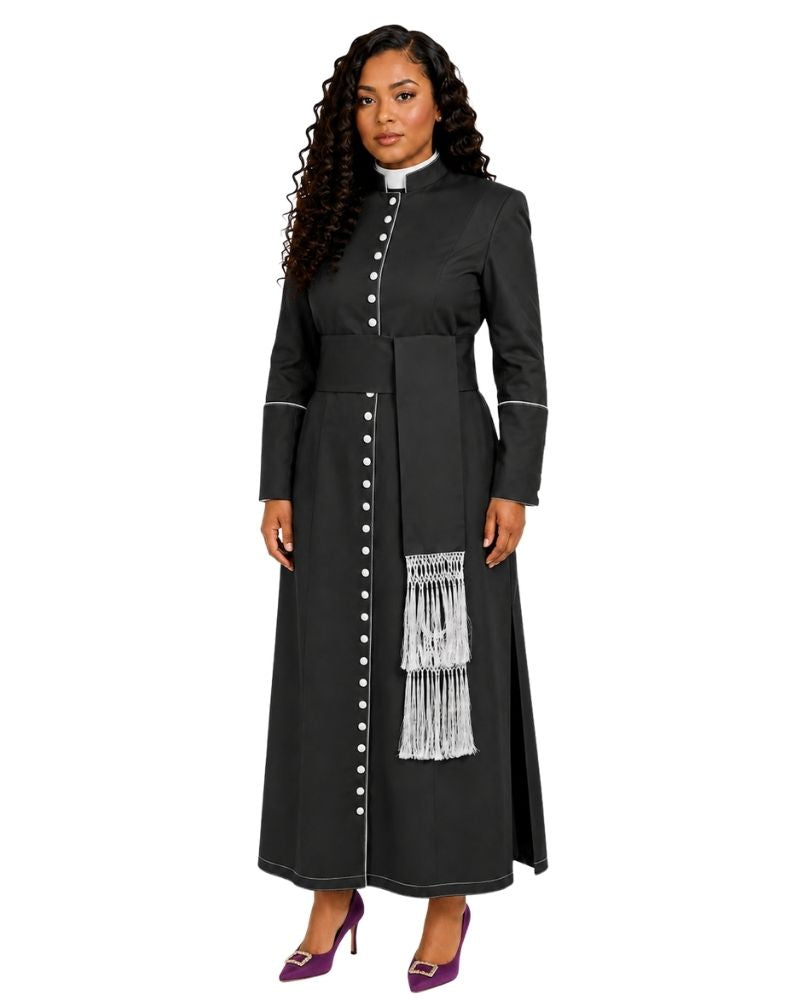 A woman modeling a black cassock with white buttons, white piping details, and a white fringe panel on the front, paired with purple heels, against a plain white background.