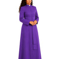 A woman modeling a long-sleeved purple clerical cassock with a high collar, front button closure, and a matching belt, shown against a plain white background.