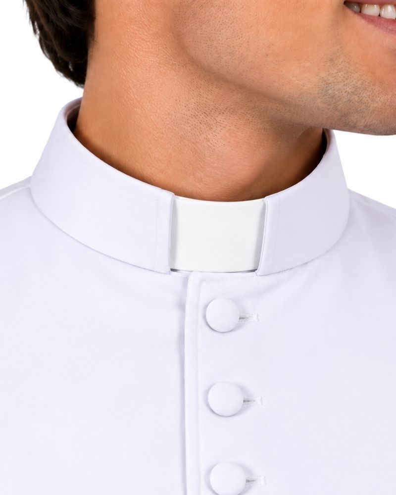 A close-up of a man wearing a Beaux White Cassock and a white button-front shirt against a plain white background.