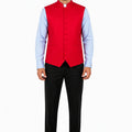 Man wearing a red vest over a light blue shirt with black pants on a white background