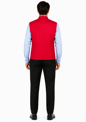 Man wearing a red vest over a light blue shirt with black pants on a white background