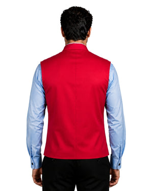 A man viewed from behind wearing a bright red sleeveless vest over a light blue dress shirt and black trousers, against a white background.