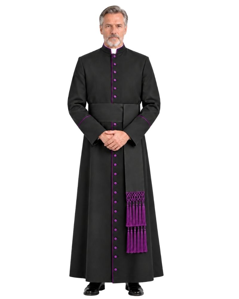 A man wearing a Black Clergy Cassock With Roman Purple Trim e with purple trim, purple buttons, and a matching purple pectoral cross, standing against a plain white background.
