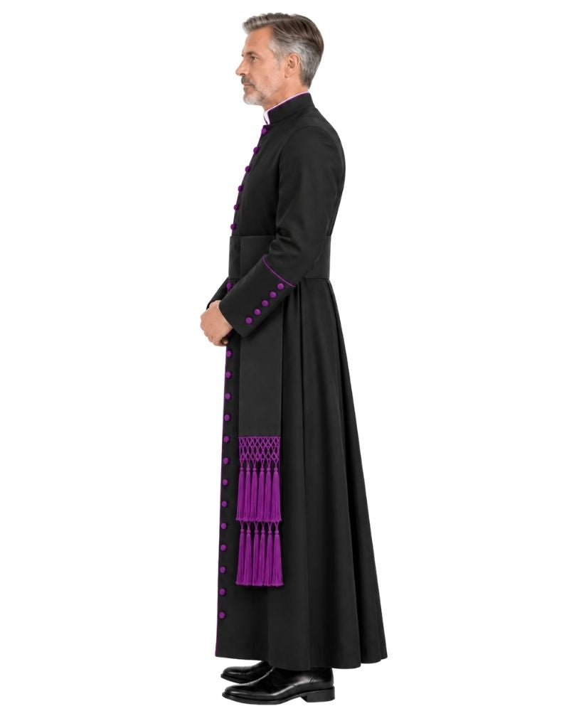 A man in profile wearing a Black Clergy Cassock With Roman Purple Trim with bright purple decorative trim, buttons, and tassels, standing against a plain white background.