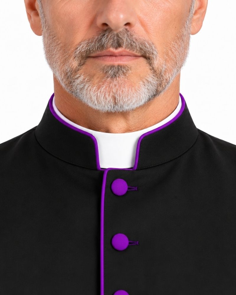 Close-up of a man wearing a Black Clergy Cassock With Roman Purple Trim with a white collar and bright purple trim and buttons, against a plain white background.