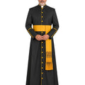 A man modeling a Black Roman Cassock With Yellow Trim with gold buttons, a yellow sash, and a matching yellow stole with fringe, against a plain white background.