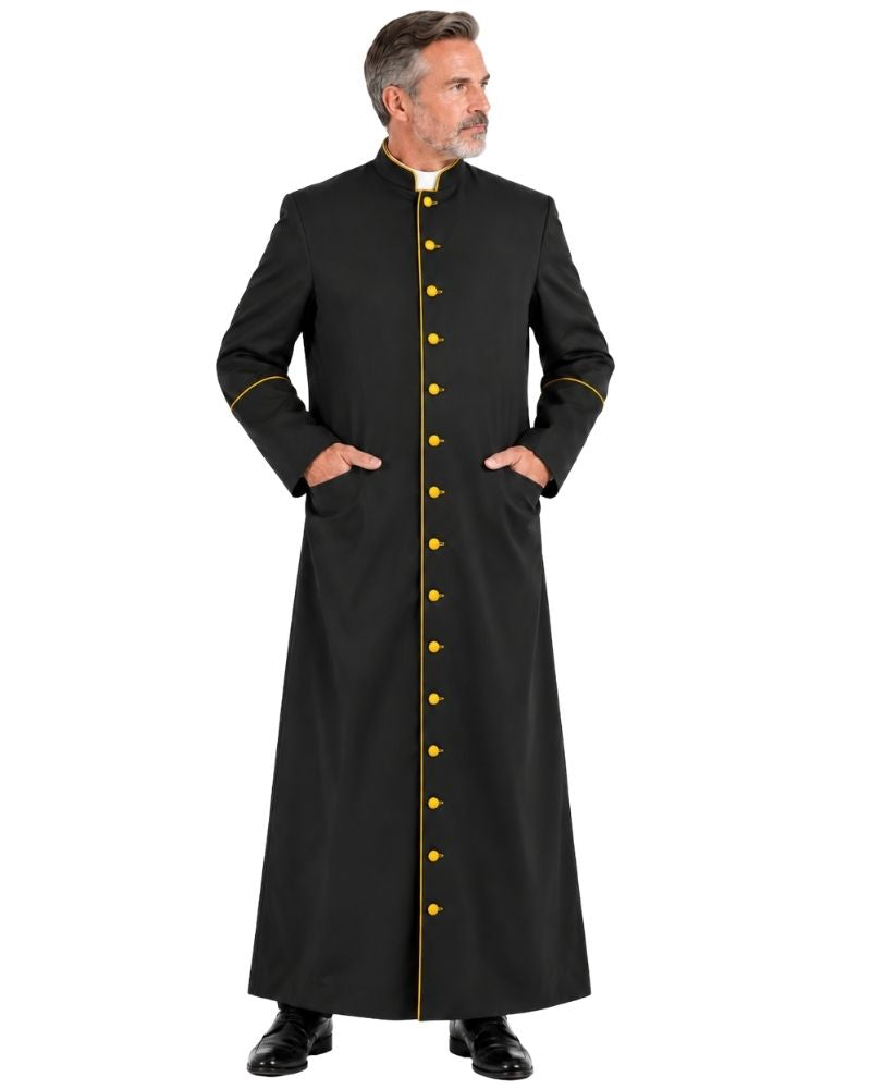 A man wearing a Black Roman Cassock With Yellow Trim, standing against a plain white background.