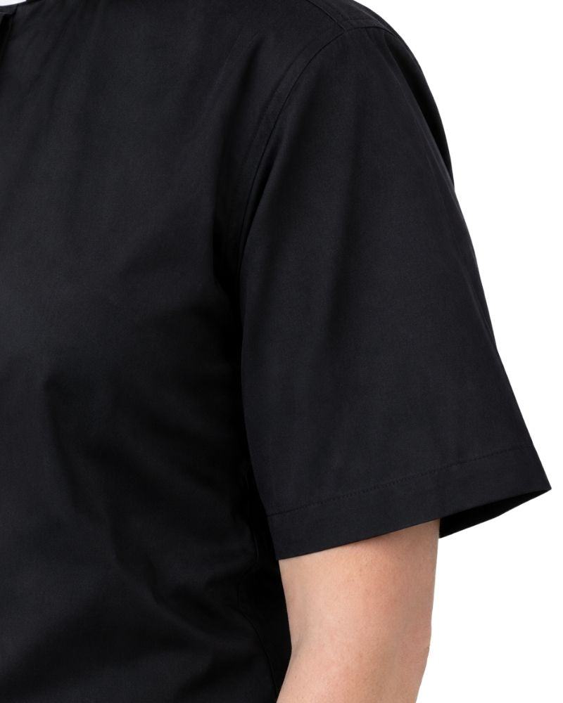 Close-up of a women wearing a plain black short-sleeve clerical shirt against a white background.