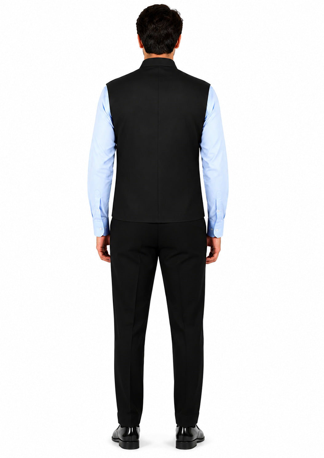 Man wearing a black vest over a light blue shirt with black pants on a white background