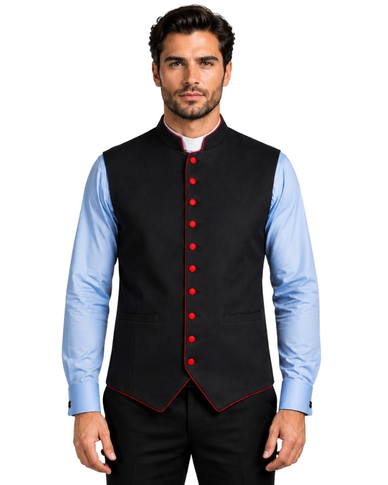A man wearing a black waistcoat vest with red button and piping details, layered over a light blue dress shirt and black trousers, against a white background.