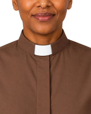 A close-up of a woman wearing a brown clerical shirt with a white collar, shown against a plain white background.