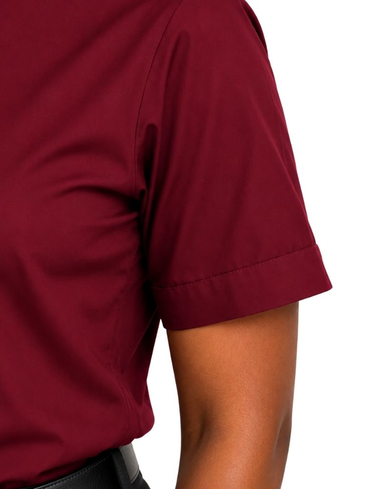 Close-up of a woman wearing a short-sleeve burgundy clerical shirt, showing the sleeve cuff and side torso against a white background.