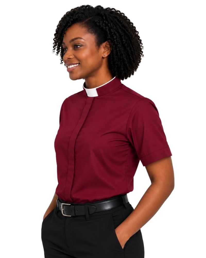 A woman wearing a burgundy short-sleeve clerical shirt with a white collar, paired with black trousers and a black belt, shown against a plain white background.