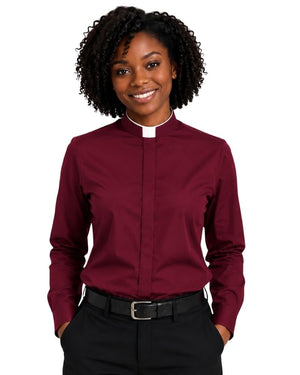 A smiling woman with curly black hair wearing a burgundy long-sleeve clerical shirt with a white collar, paired with black trousers and a black belt, against a plain white background.