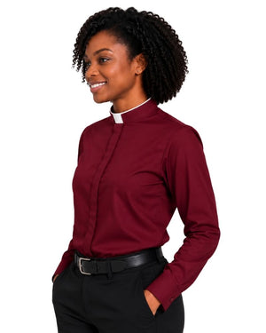 A woman with curly black hair wearing a burgundy long-sleeve clerical shirt with a white collar, paired with black trousers and a black belt, shown against a plain white background.
