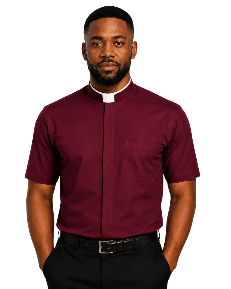 A man wearing a burgundy short-sleeve clerical shirt with a white collar, paired with black trousers and a black belt, standing against a solid white background.
