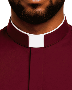 Close-up of a man wearing a burgundy clerical collar shirt with a white clerical collar, showing the neck, beard, and upper chest against a plain white background.