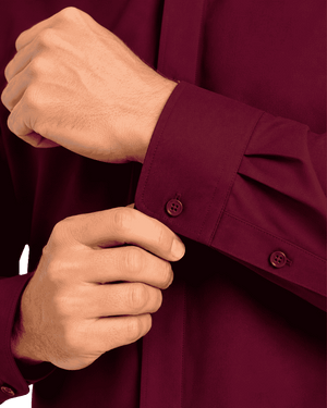 Close-up of a man hands adjusting the cuff of a burgundy long-sleeve clerical shirt.