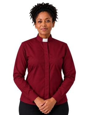 A smiling woman with curly black hair wearing a long-sleeve burgundy clerical shirt with a white collar, paired with black trousers and a black belt, against a plain white background.