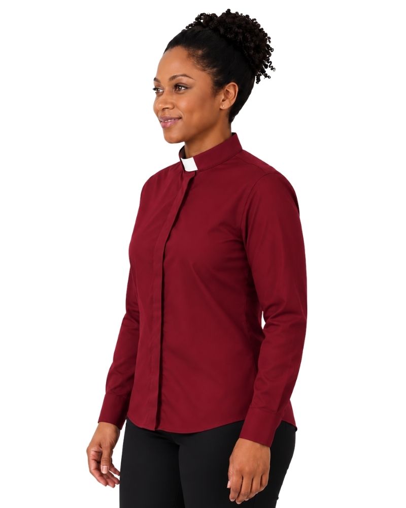 A woman wearing a long-sleeve burgundy clerical shirt with a contrasting white collar, paired with black trousers and a black belt, shown in a side-profile view against a plain white background.
