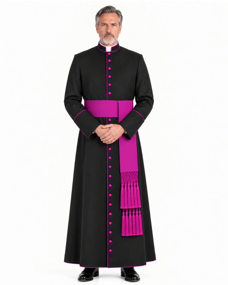 A man wearing a Classic Clergy Cassock With Magenta Trim, a matching magenta sash, and magenta buttons, standing against a plain white studio background.