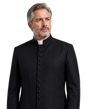 A man with gray hair and a beard wearing a black clerical-style Cassock over a white collar, photographed against a plain white background.
