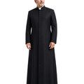 A man modeling a long black clerical Cassock with a high collar and a row of front buttons, paired with a white clerical collar, against a plain white background.