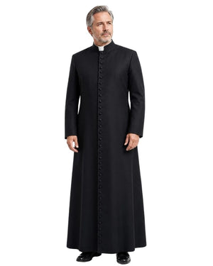 A man modeling a long black clerical Cassock with a high collar and a row of front buttons, paired with a white clerical collar, against a plain white background.