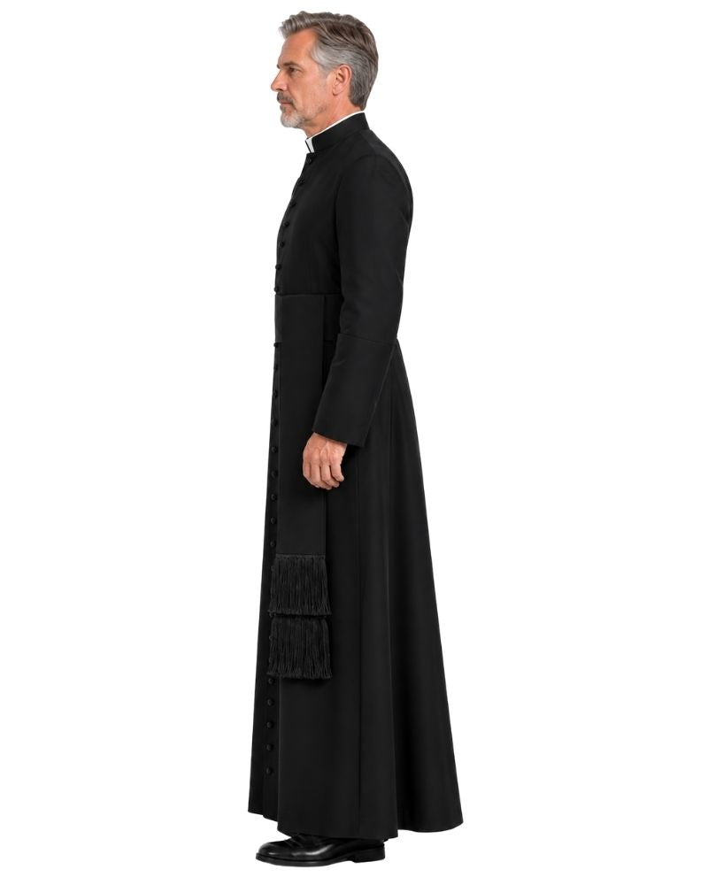 A man shown in profile wearing a long black clerical robe with a high collar, standing against a plain white background.