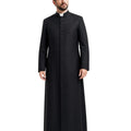 A man modeling a long black clerical cassock with a high stand collar, front button placket, and a white clerical collar, set against a plain white background.