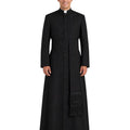 A man wearing a long black clerical cassock with a high collar, front button closure, waist tie, and a matching black scapular with fringe, photographed against a plain white background.