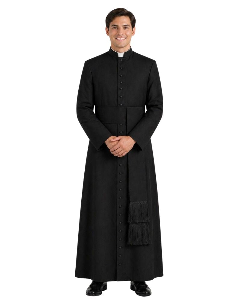 A man modeling a long black clerical cassock with a high collar, front buttons, and a small white clerical collar, photographed against a plain white background.