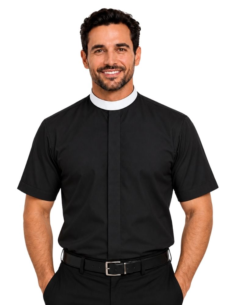 A smiling man wearing a black short-sleeve clerical shirt with a white collar, paired with black trousers and a black belt, against a plain white background.