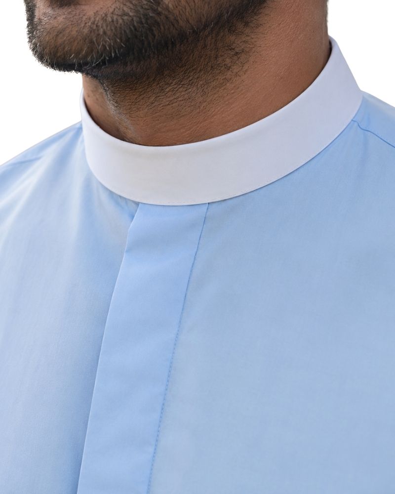 Close-up of a man wearing a light blue shirt with a contrasting white high collar, showing the neck, beard, and collar detail.