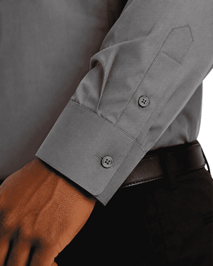 Close-up of a gray long-sleeve clerical shirt worn with a black belt and dark trousers, showing the cuff and button details.