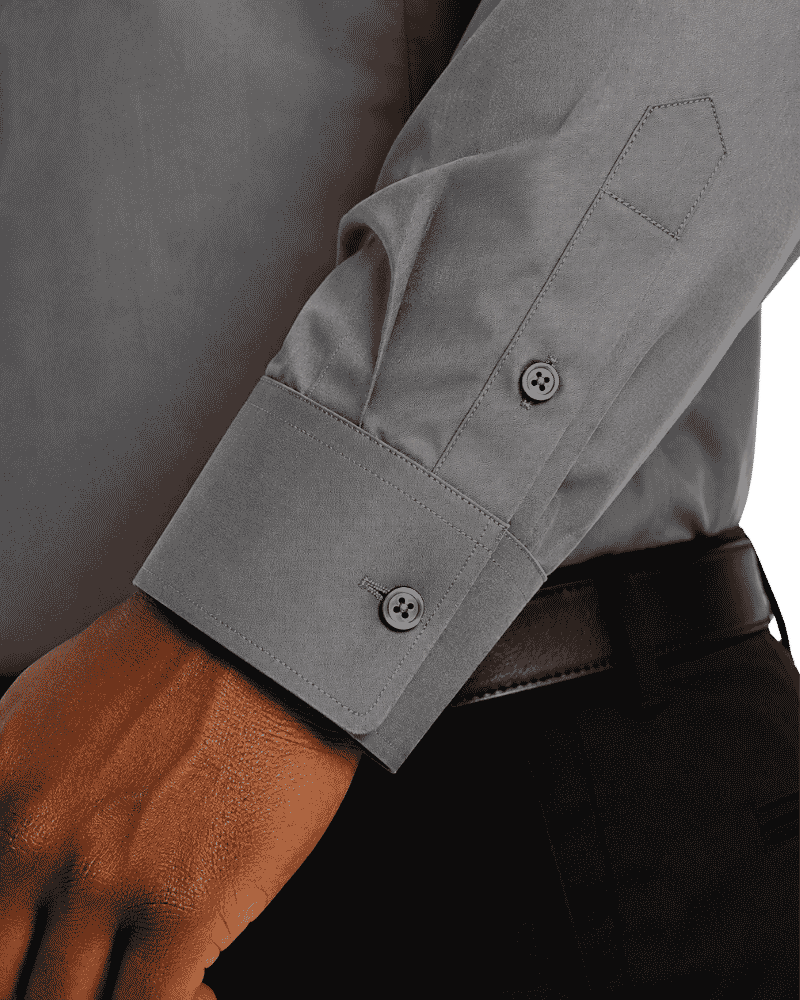 Close-up of a gray long-sleeve clerical shirt worn with a black belt and dark trousers, showing the cuff and button details.