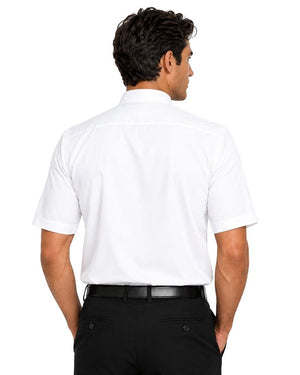 A man viewed from the back wearing a white short-sleeve clerical shirt and black trousers, photographed against a plain white studio background.