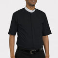 Man wearing a black shirt with a white collar on a plain background
