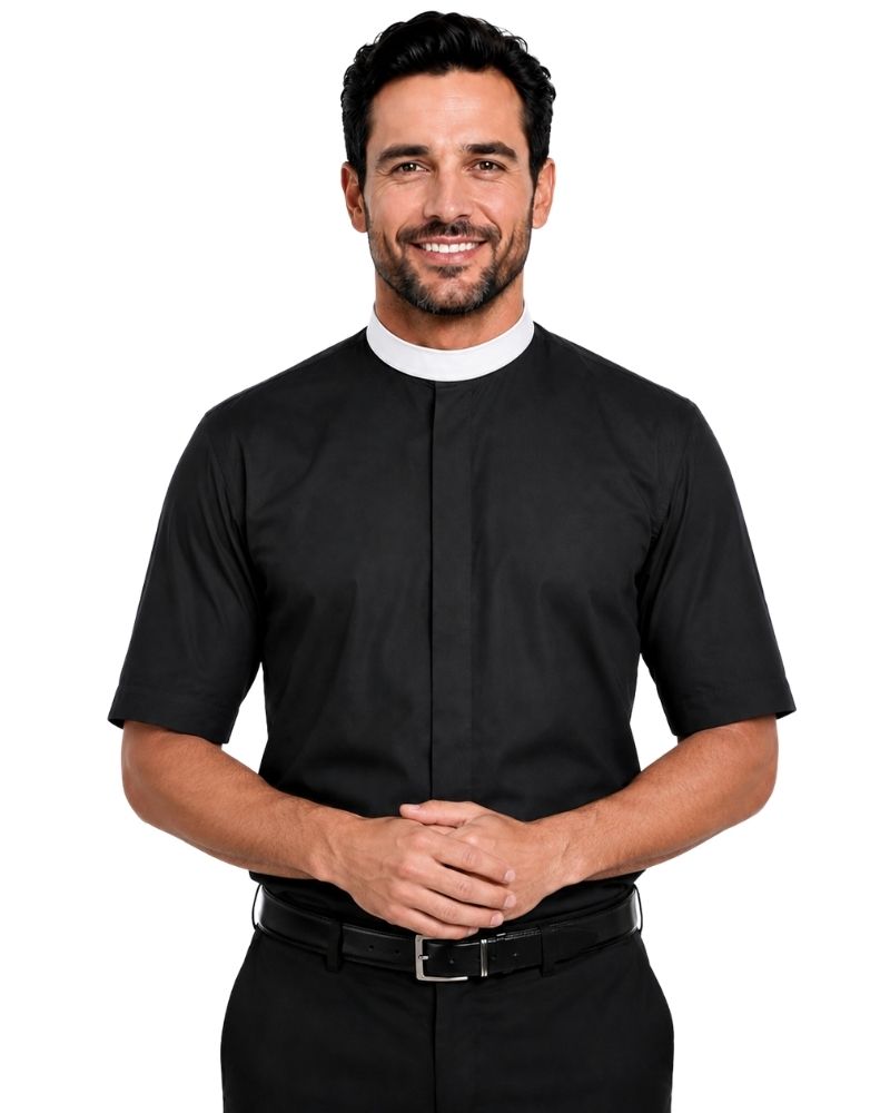 A smiling man wearing a black short-sleeve clerical shirt with a white collar, paired with black trousers and a black belt, against a plain white background.