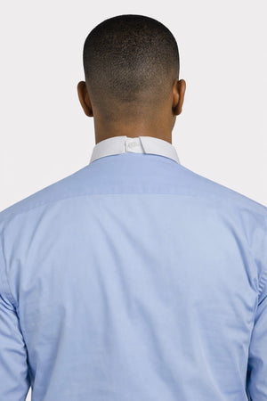 Man wearing a light blue shirt with a white collar against a plain background
