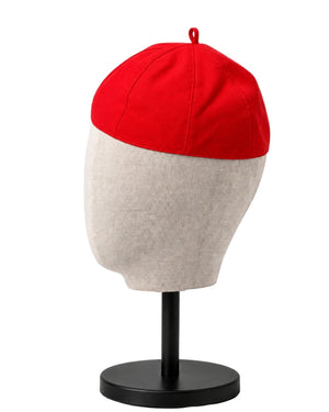A clergy zucchetto cap with a bright red top and a light beige lower half, displayed on a fabric mannequin head mounted on a black stand against a white background.