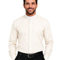 A smiling man wearing a cream-colored long-sleeve clerical shirt with a high mock neck, paired with black trousers and a black belt, against a plain white background.