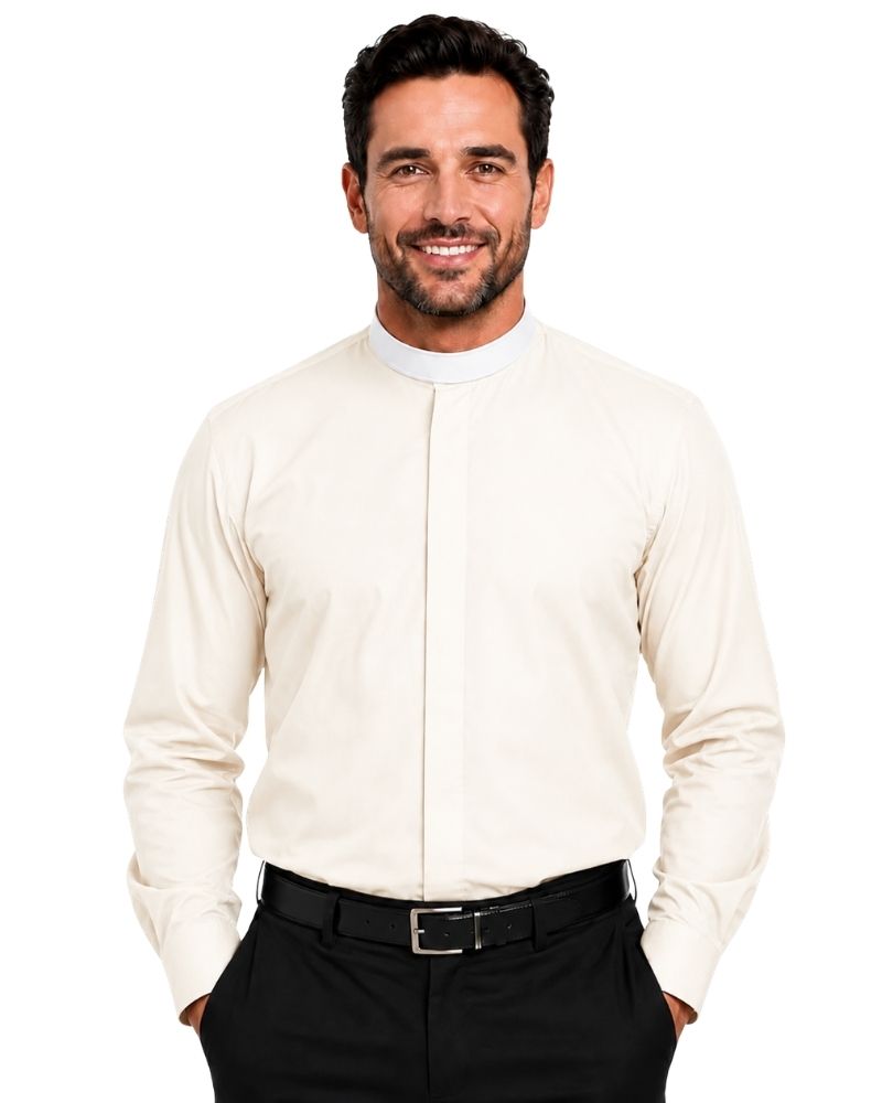 A smiling man wearing a cream-colored long-sleeve clerical shirt with a high mock neck, paired with black trousers and a black belt, against a plain white background.