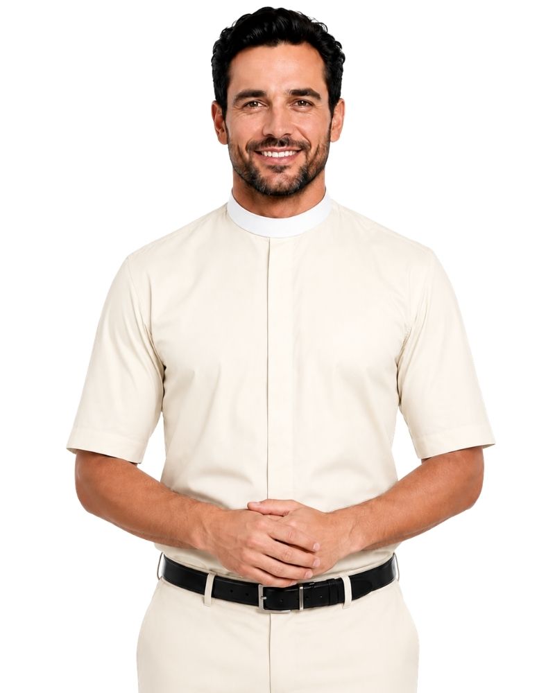 A smiling man wearing a cream-colored short-sleeve clerical shirt with a mock neck and front button placket, paired with matching trousers and a black belt, against a plain white background.