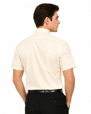 A man shown from the back wearing a short-sleeve cream-colored clerical shirt tucked into black trousers with a black belt, against a plain white background.
