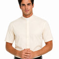 A man wearing a cream-colored short-sleeve clerical shirt with a white collar, paired with black trousers and a black belt, against a plain white background.