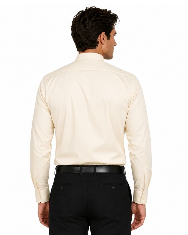 A man viewed from the back wearing a cream-colored long-sleeve clerical shirt, black trousers, and a black belt against a plain white background.