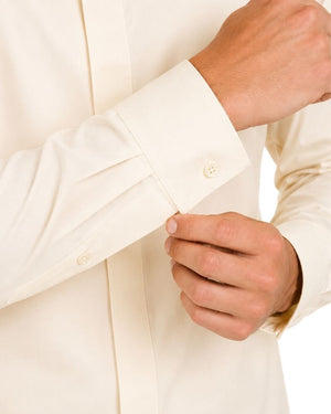 Close-up of a man's hands adjusting the cuff of an off-white long-sleeve clerical shirt.