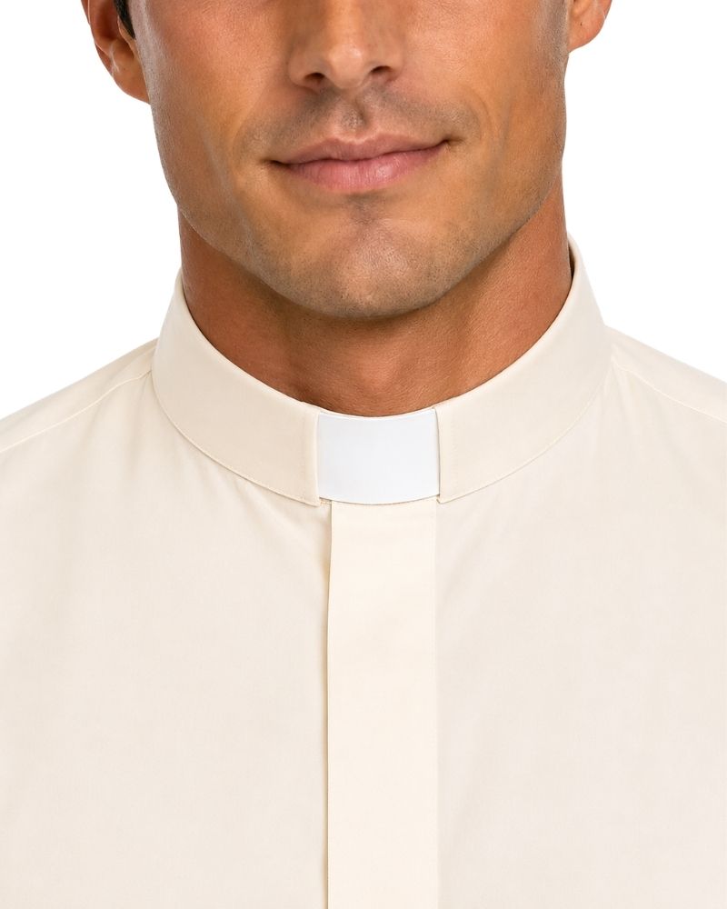 Close-up of a man wearing a cream-colored clerical shirt with a white collar tab, shown against a plain white background.